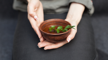 Herbal tea in a ceramic plate in female hands. The concept of nontraditional treatment of colds. Flu. Healthy Eating and Vitamins.の写真素材