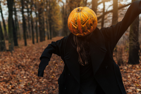 Portrait of a scary Jack-lantern with a pumpkin on his head. Halloween legend. Dressed in black coat. Autumn forestの写真素材