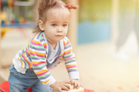 A little girl with two tails in a striped blouse plays a summer sunny day in the playground Summer family leisureの写真素材