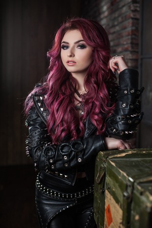 redhead adult girl biker in the leather wear standing indoorの写真素材