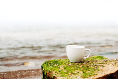 cup of coffee on the sea water and stone background. Sea freshness morning concept.の写真素材
