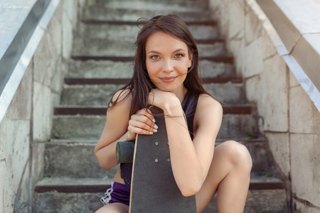 Beautiful young girl with a long board in the city. The concept of modern youth. Active fun holidayの写真素材