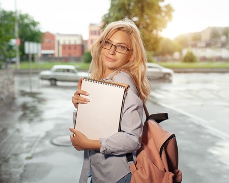 Enthusiastic Happy beautiful young girl smiling and holding pile of books standing near campus lifestyle positivity academic graduating university school.の写真素材
