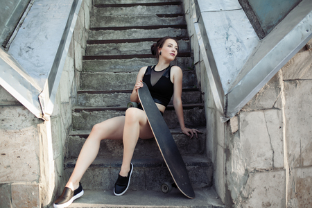 Beautiful young girl with a long board in the city. The concept of modern youth. Active fun holidayの写真素材