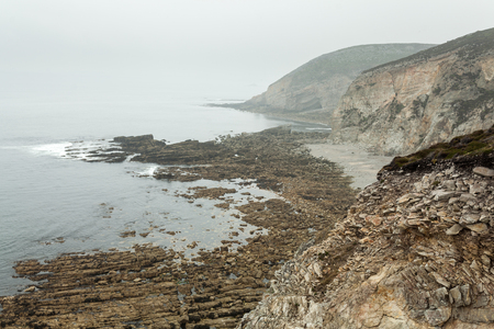 Summer Atlantic rocky coast view Big stony rockfall on precipice shore and ocean surf waves.の写真素材