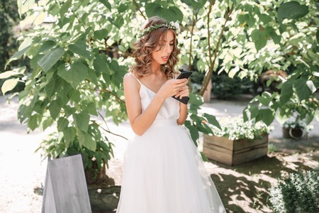 Wedding. Attractive bride with beautiful bouquet and mobile phone.の写真素材