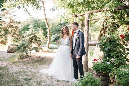 Bride and groom at wedding Day walking Outdoors on summer nature. Bridal couple, Happy Newlywed woman and man embracing in green park. Loving wedding couple outdoor.の写真素材