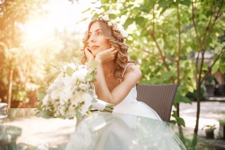 a young bride sits at a glass table with her hands folded at the chin. Bored.の写真素材