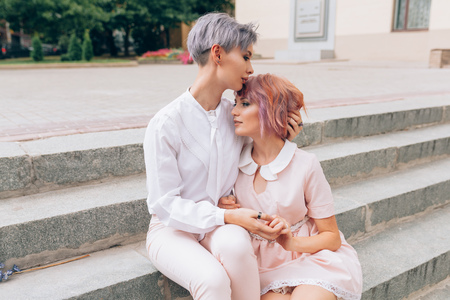 Stylish lesbian couple hugging on the stairs in the cityの写真素材
