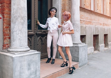Stylish lesbian couple holding hands near the old building in the city