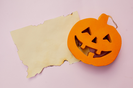 Halloween pumpkin with a burnt paper on a pink backgroundの写真素材