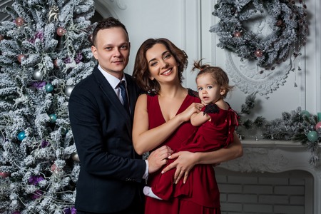 Mom dad and daughter dressed in a stylish suit and elegant red evening dress at a secular party in...