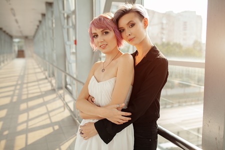 people, homosexuality, same-sex marriage, travel and gay love concept - close up of happy women couple hugging over metall bridge. Two girlfriend walkingの写真素材