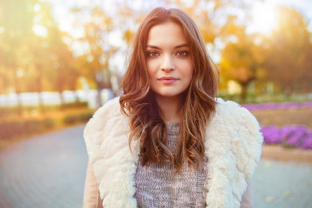 A beautiful young girl walks through the autumn park on the background of brightly colored leaves. Autumn concept, fashion and style.の写真素材