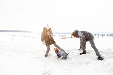 A young couple, a man and a woman are walking with their dog in the winter snow-covered forest. Winter leisure. Dog lovers Happy people and positive emotions conceptの写真素材