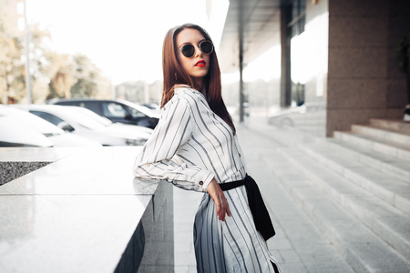 Summer sunny lifestyle fashion portrait of young stylish hipster woman in sunglasses walking on the street, wearing cute trendy outfit European tripの写真素材