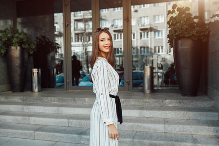 Summer sunny lifestyle fashion portrait of young stylish hipster woman with sunglasses walking on the street, wearing cute trendy outfit enjoy her weekends, travel alone.の写真素材