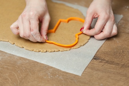 cooking and home concept - close up of female hands making cookies from fresh dough at homeの写真素材