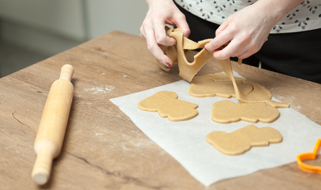 cooking and home concept - close up of female hands making cookies from fresh dough at homeの写真素材