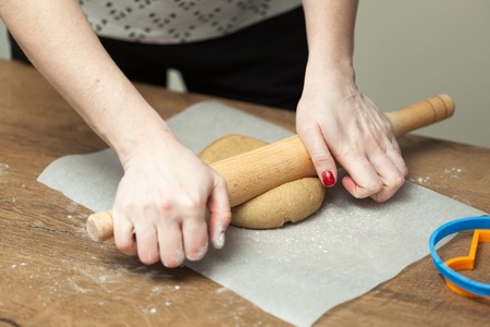 cooking and home concept - close up of female hands making cookies from fresh dough at homeの写真素材