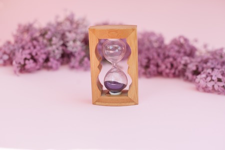 Sand running through the bulbs of an hourglass measuring the passing time in a countdown to a...