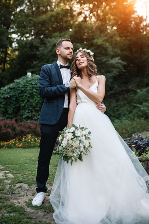 Bride and groom at wedding Day walking Outdoors on summer nature. Bridal couple, Happy Newlywed woman and man embracing in green park. Loving wedding couple outdoor.の写真素材