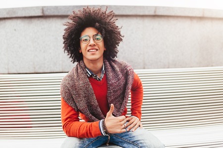 Young handsome curly guy showing thumbs up. Happy foreign student smiling and happy with life positive emotionの写真素材