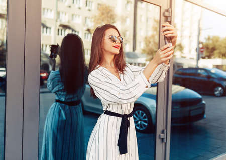 young beauty woman make selfie for self smartphone, outdoor portrait, fashion model, pretty girl, hipster, lips red, make up, close up, beauty street photo.の写真素材