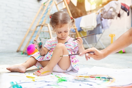 Child Girl Drawing Picture Outdoors in Summer Little girl drawing with paint on the backyardの写真素材