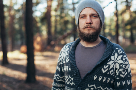 a young man with a beard walks in a pine forest. Portrait of a brutal bearded man Autumn forest tourism conceptの写真素材
