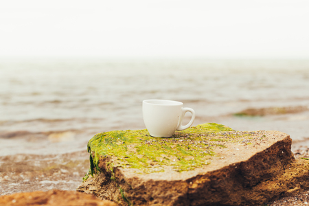 cup of coffee on the sea water and stone background. Sea freshness morning concept.の写真素材