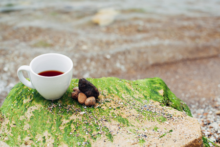 cup of coffee on the sea water and stone background. Sea freshness morning concept.の写真素材