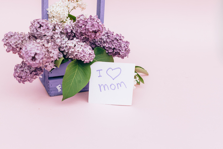 Beautiful bouquet of purple lilac and card on purple paper background Bouquet of lilac flowers in basket. paper card with sample text Happy Motherの写真素材