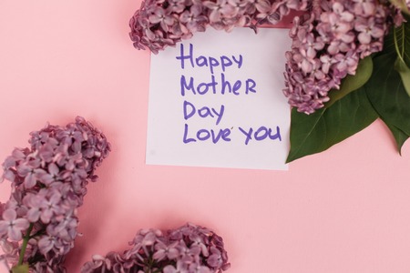 Beautiful bouquet of purple lilac and card on purple paper background Bouquet of lilac flowers in basket. paper card with sample text Happy Motherの写真素材