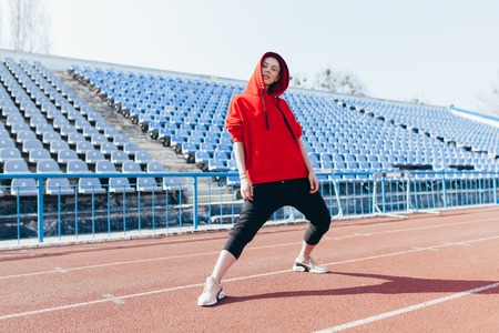 Beautiful girl in sportswear standing on the running track and preparing to run. Morning warm-up before exercise training.の写真素材