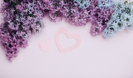 Lilac branches and two pink heart on a light pink background empty space for your text, top view. One big and one small heart like simbol of loveの写真素材