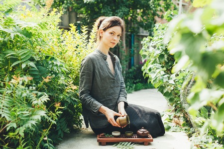 Oriental Master of tea ceremony in summer park. Traditional tea party on the nature with woman...