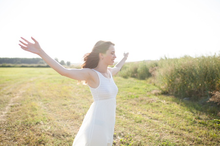 Portrait of woman on the summer field on light background. Pretty young girl. Sunny summer day. Green grass field. Summer background. Outdoor portrait, day light. Rural landscape.の写真素材