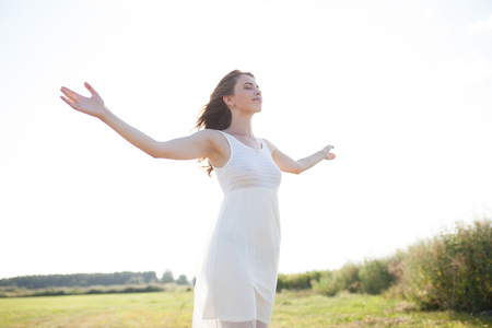 Portrait of woman on the summer field on light background. Pretty young girl. Sunny summer day. Green grass field. Summer background. Outdoor portrait, day light. Rural landscape.の写真素材