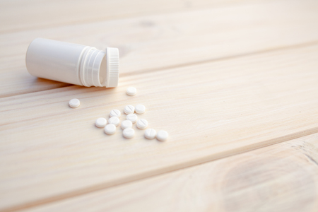 Pills and pill bottle on white wooden background Health care medicine mock up conceptの写真素材
