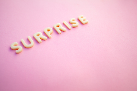 Surprise word written in voluminous white letters on a beautiful pink background. greting cardの写真素材