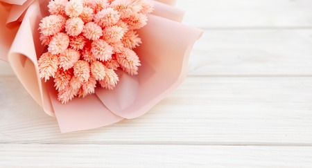 Beautiful bouquet of dry pink flowers on a wooden white background. Minimalism, space for text. Gift Card. abstract spring theme.の写真素材