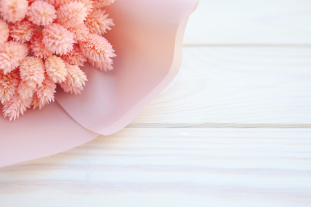Beautiful bouquet of dry pink flowers on a wooden white background. Minimalism, space for text. Gift Card. abstract spring theme.の写真素材