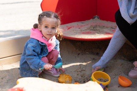 Cute little caucasian girl on the playground, happy child with pleasure spending time outdoors,...