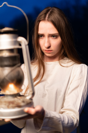 Mysterious mystical girl in a dark night forest with a kerosene lamp in her hands Halloween conceptの写真素材