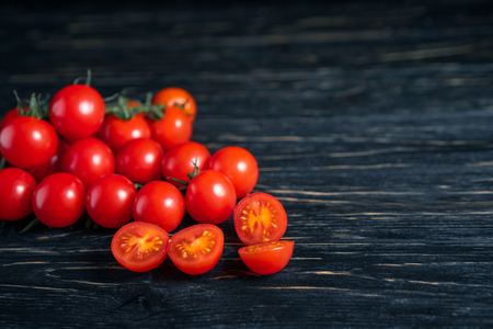 Cherry tomatoes on the dark wooden table. Juicy ripe vegetables on a black background. Healthy eating. vegetarian foodの写真素材