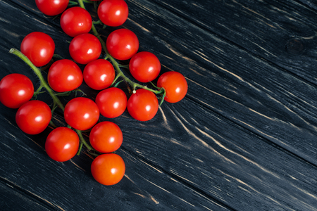Cherry tomatoes on the dark wooden table. Juicy ripe vegetables on a black background. Healthy eating. vegetarian foodの写真素材