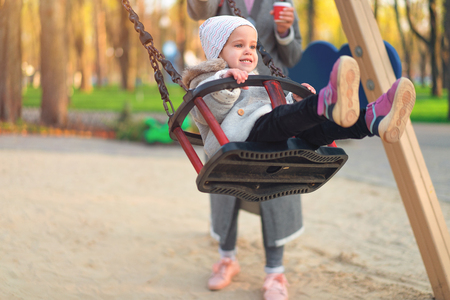 Happy child girl on swing in sunset fall. Little kid playing in the autumn on the nature park Adorable girl having fun on a swing on beautiful autumn dayの写真素材