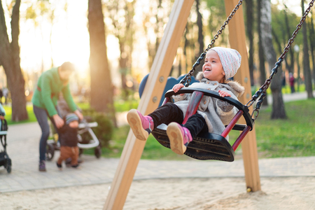 Happy child girl on swing in sunset fall. Little kid playing in the autumn on the nature park Adorable girl having fun on a swing on beautiful autumn dayの写真素材