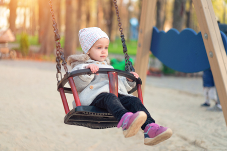 Happy child girl on swing in sunset fall. Little kid playing in the autumn on the nature park Adorable girl having fun on a swing on beautiful autumn dayの写真素材